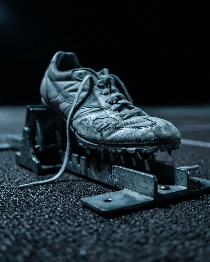 A worn sprint shoe on a starting block